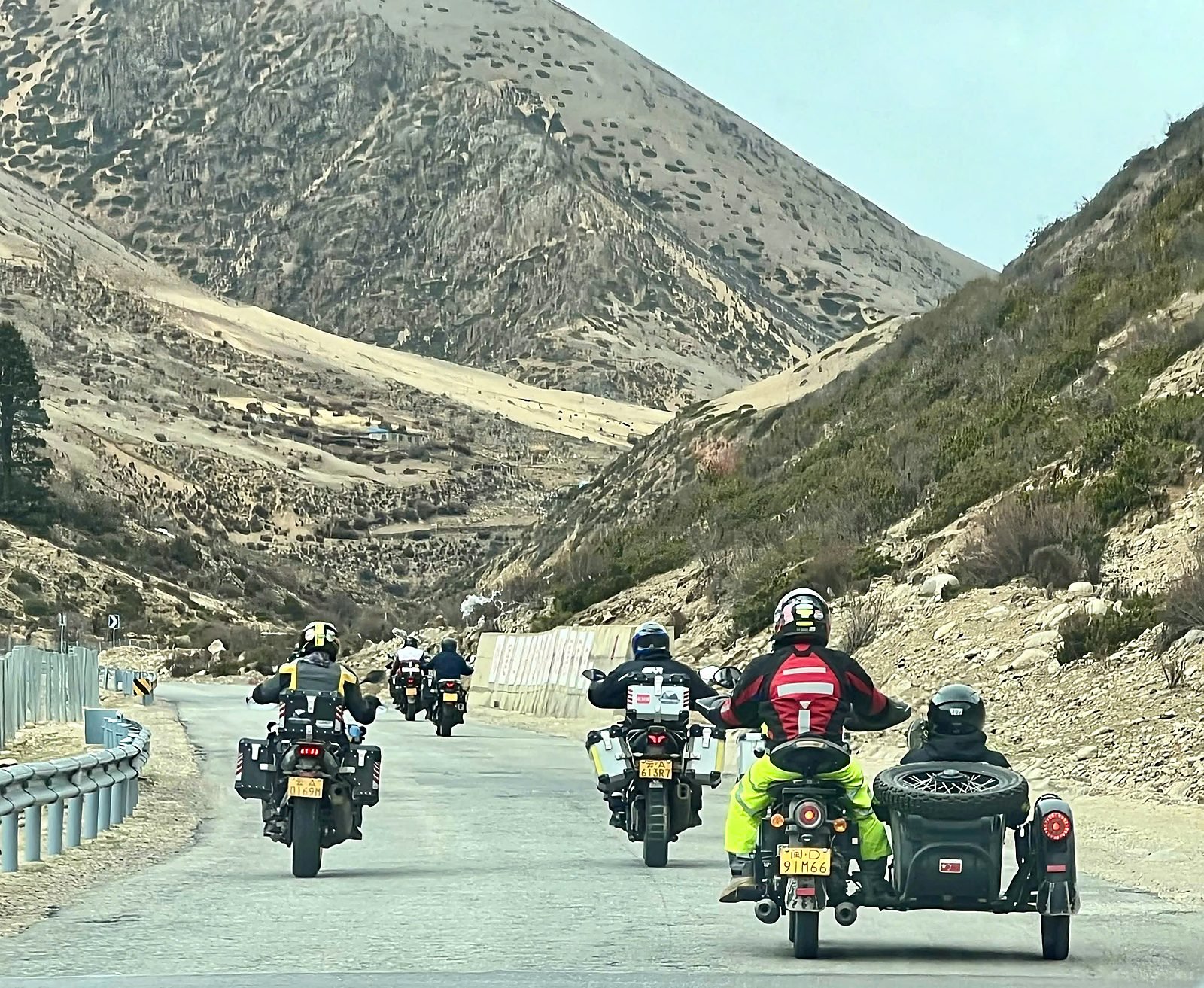 Đoàn xe mô tô và một xe sidecar chạy trên đường đèo giữa thung lũng núi trọc của G318