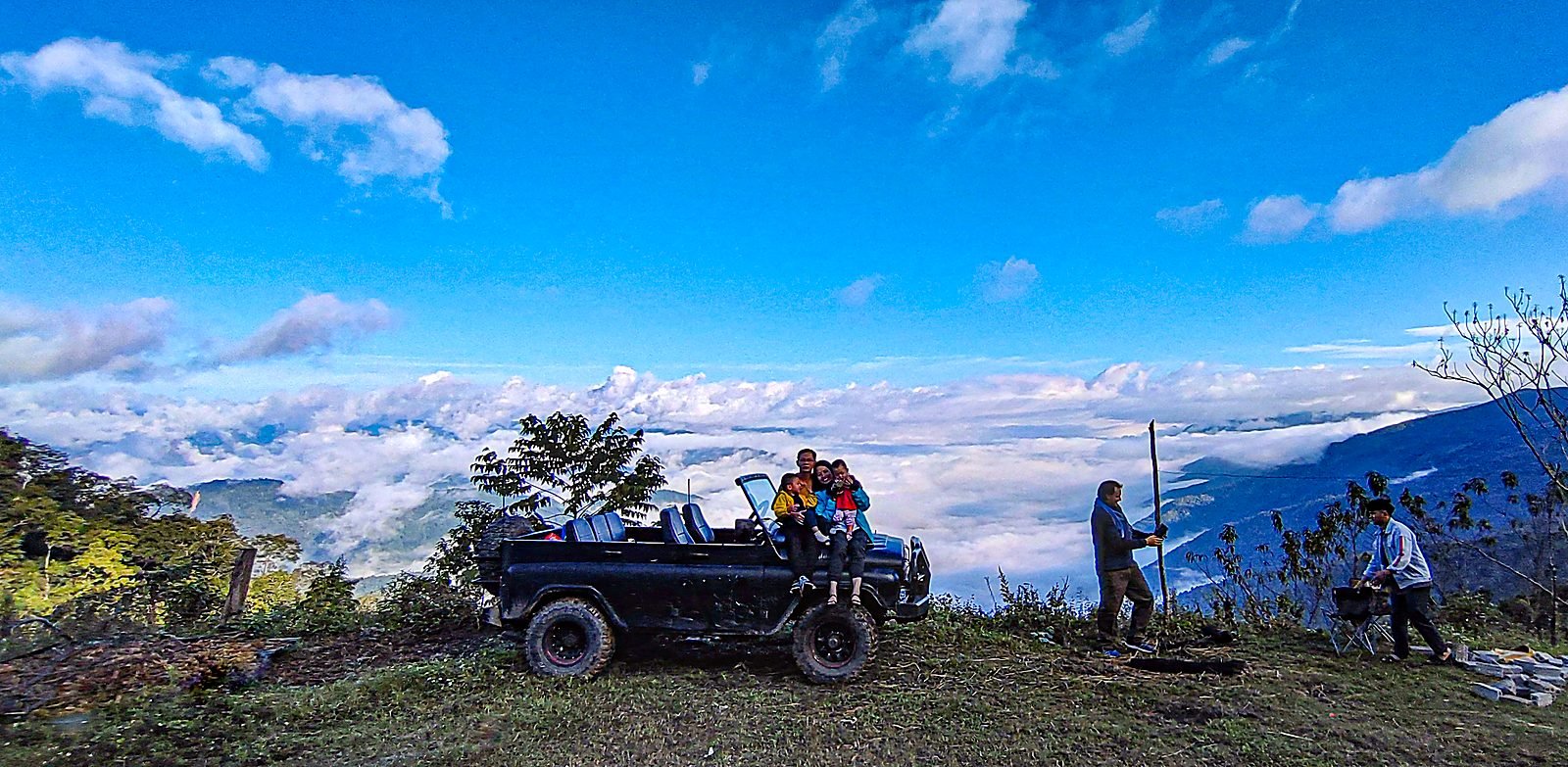 Chiếc xe UAZ đỗ trên đỉnh đồi, biển mây trắng trải dài phía sau